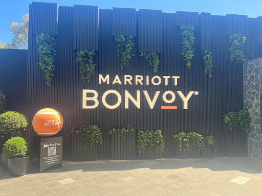 Marriott Bonvoy brand activation wall at the Australian Open 2026 with large white logo text, integrated greenery, and an orange tennis ball display.